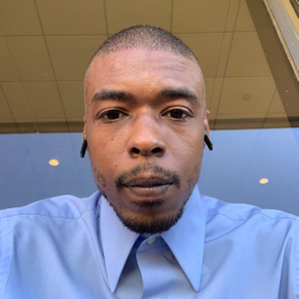 A candid photograph of Logan Willoughby wearing a blue collared shirt.